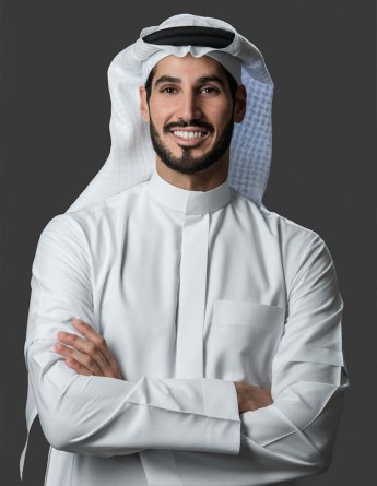 a happy hassan jameel poses in a white outfit with a smile and folded arms